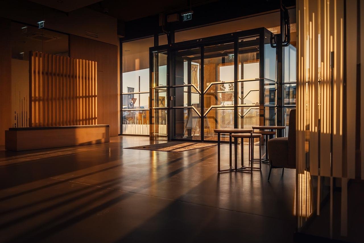 Glass entrance doors in a commercial building lobby with illuminated exit signs above them